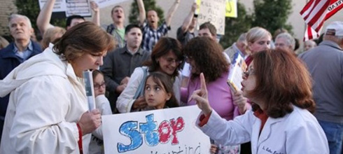 Doctor and protester argue while little girl holds a sign.