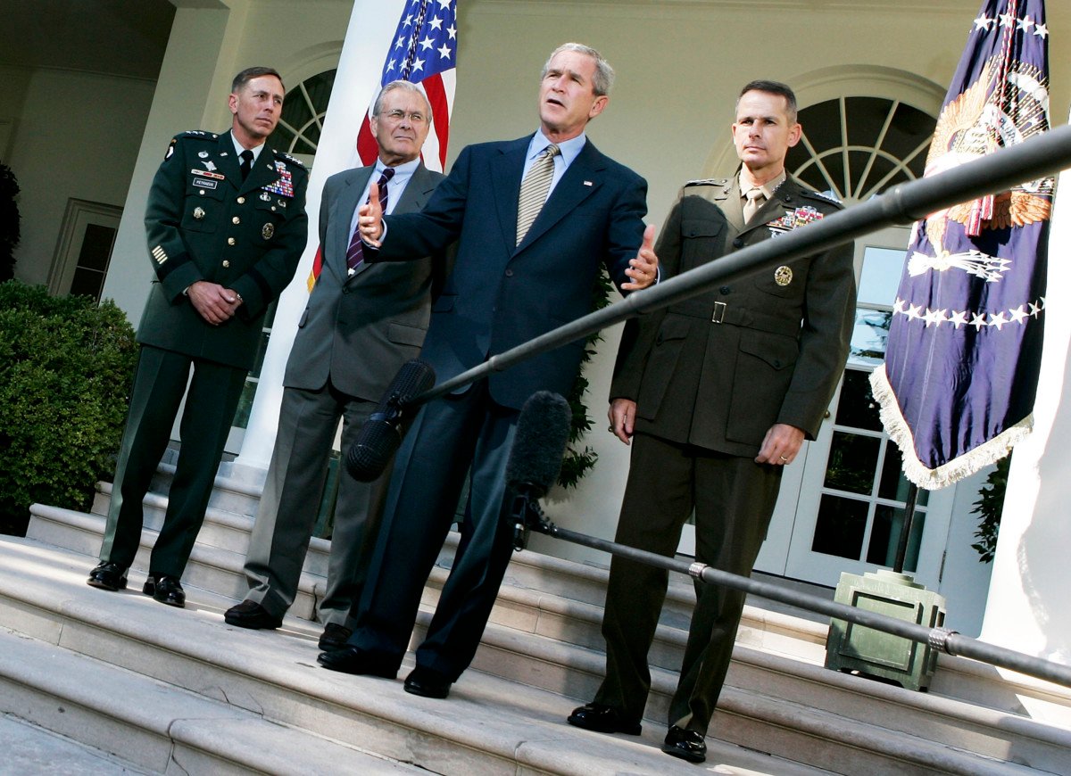 President George W. Bush speaks as Lt. Gen. David Petraeus, Secretary of Defense Donald Rumsfeld (2nd L), and Chairman of the Joint Chiefs of Staff Gen. Peter Pace (R) listen during a post-meeting briefing at the Rose Garden of the White House October 5, 2005, in Washington, DC.