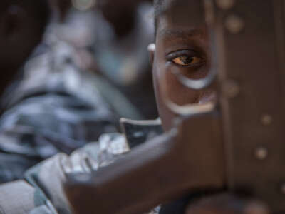 A newly released child soldier looks through a rifle trigger guard during a release ceremony for child soldiers in Yambio, South Sudan, on February 7, 2018.