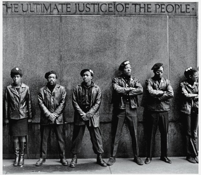 View of a line of Black Panther Party members as they stand outside the New York City courthouse under a portion of an Abraham Lincoln quote which reads "The Ultimate Justice of the People," New York, New York, April 11, 1969.