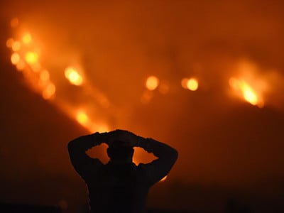 A man watches the Thomas Fire in the hills above Carpinteria, California, December 11, 2017. The Thomas Fire in California's Ventura and Santa Barbara counties has consumed more than 230,000 acres over the past week making it the fifth largest fire in the state's history.