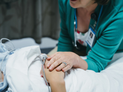 Caucasian doctor comforting patient in hospital bed.