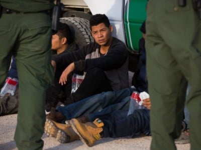 Immigrants wait to be transported to a central processing center shortly after they crossed the border from Mexico into the United States on Monday, March 26, 2018, in the Rio Grande Valley Sector near McAllen, Texas.