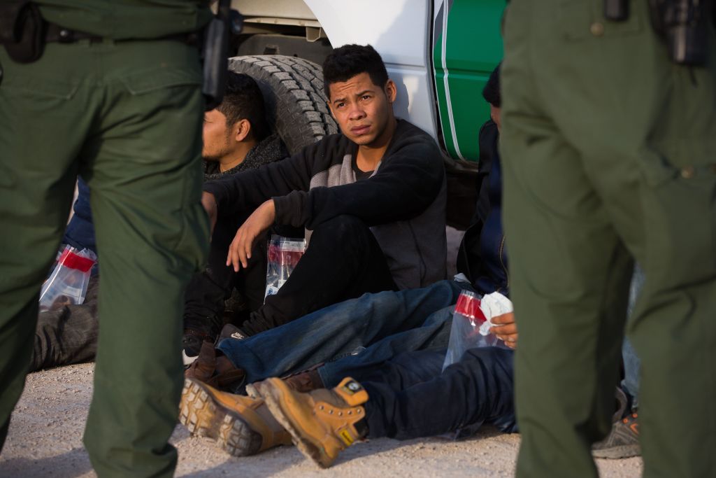 Immigrants wait to be transported to a central processing center shortly after they crossed the border from Mexico into the United States on Monday, March 26, 2018, in the Rio Grande Valley Sector near McAllen, Texas.