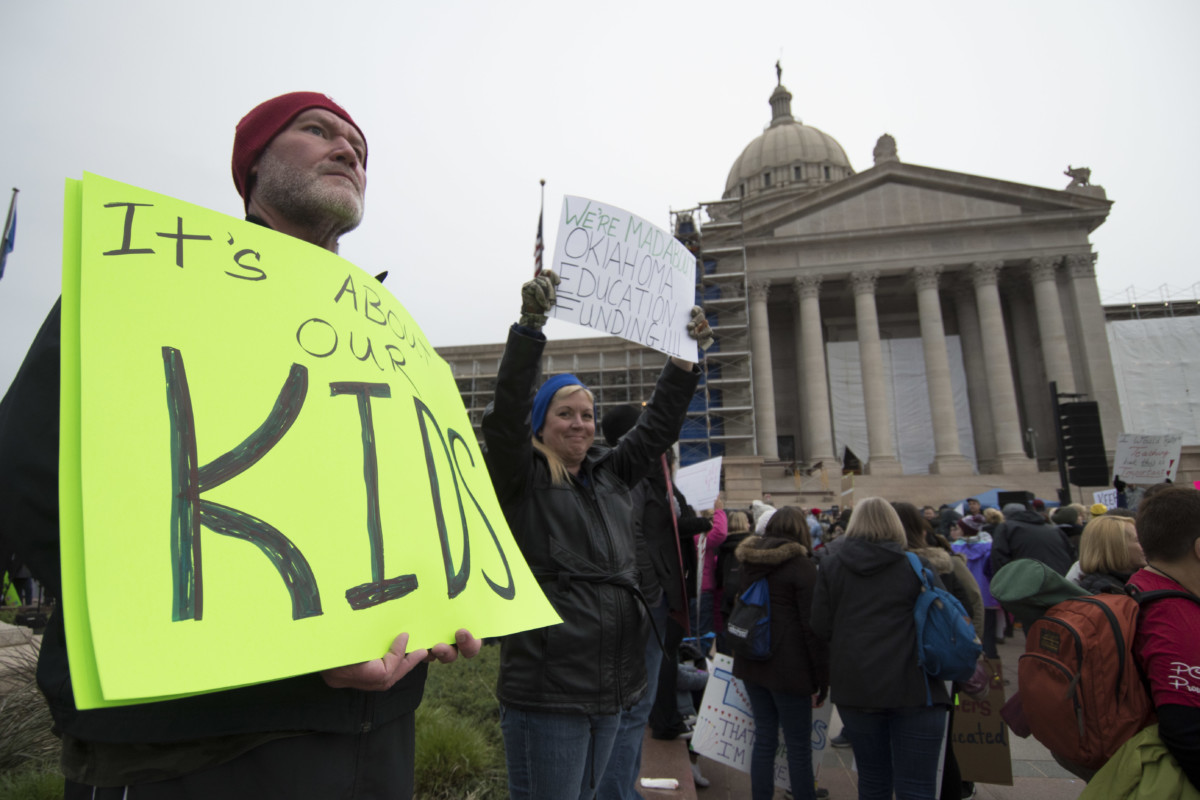 Kent Scott, a teacher from Tecumseh, Oklahoma, holds a protest sign at the state capitol on April 2, 2018, in Oklahoma City, Oklahoma. Thousands of teachers and supporters rallied Monday at the state Capitol calling for higher wages and better school funding.