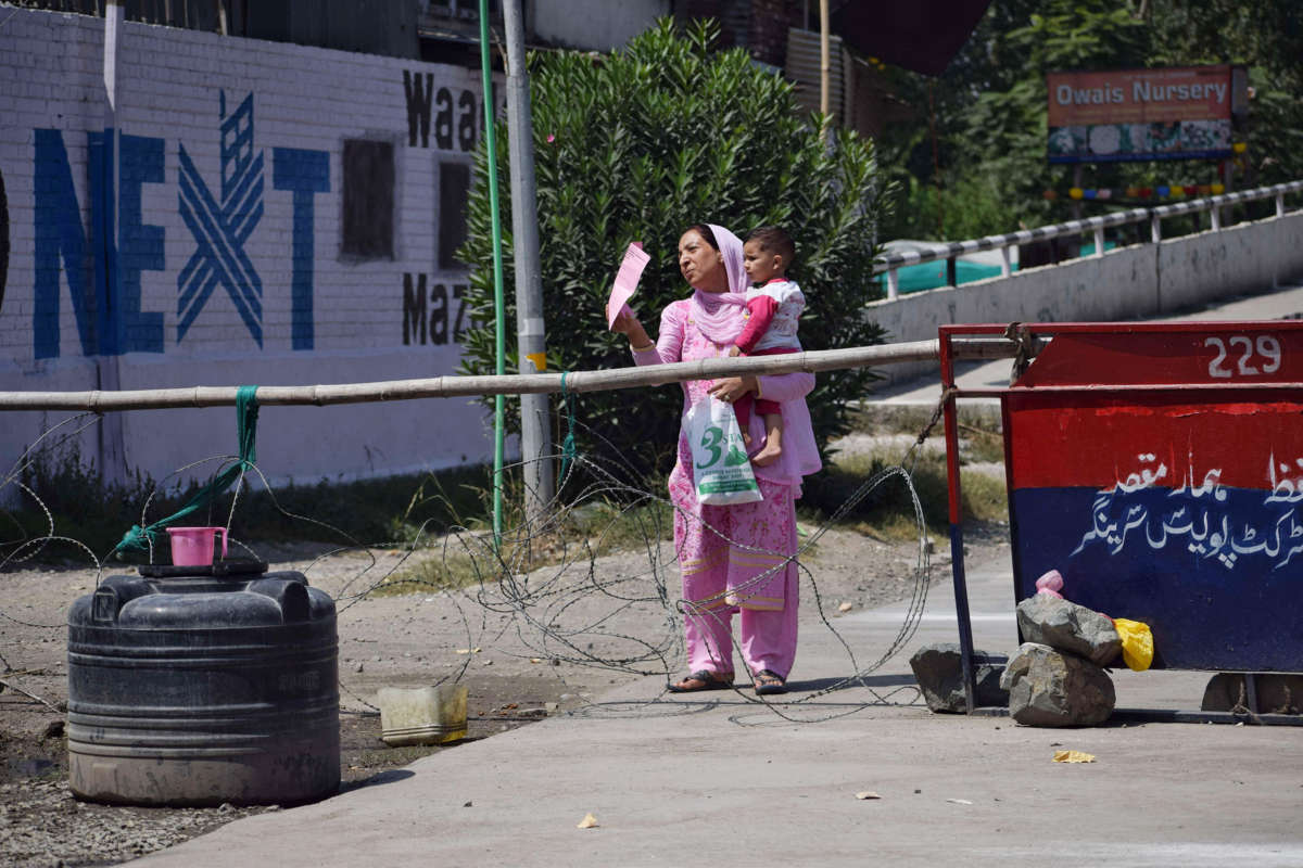 A woman wearing pink displays a piece of paper