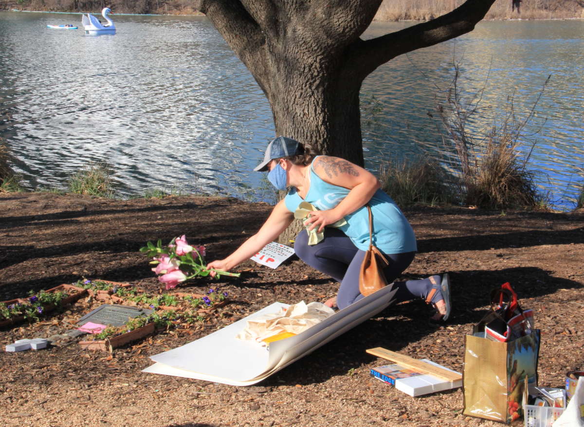 A woman leaves flowers at the Homeless Memorial and Tree of Remembrance along the south bank of Lady Bird Lake on February 21, 2021, in honor of the unhoused people who lost their lives during last week’s winter storm and blackout in Texas.