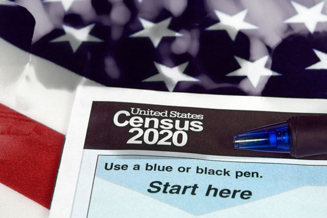A crowd of people overlaid on the USA flag behind a census form.