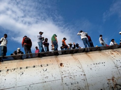 Dozens of Central American immigrants ride atop a cargo train passing through the border area in the south of Mexico, on 25 May 2010.