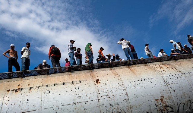 Dozens of Central American immigrants ride atop a cargo train passing through the border area in the south of Mexico, on 25 May 2010.