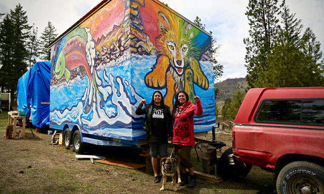 Mayuk (left) and Kanahus Manuel (right), founders of the Tiny House Warriors, in front of a completed tiny house on the Neskolinth Reserve outside of Kamloops, British Columbia.