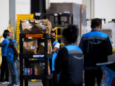 An Amazon delivery driver pushes a cart of groceries to load into a vehicle outside of a distribution facility on February 2, 2021, in Redondo Beach, California.