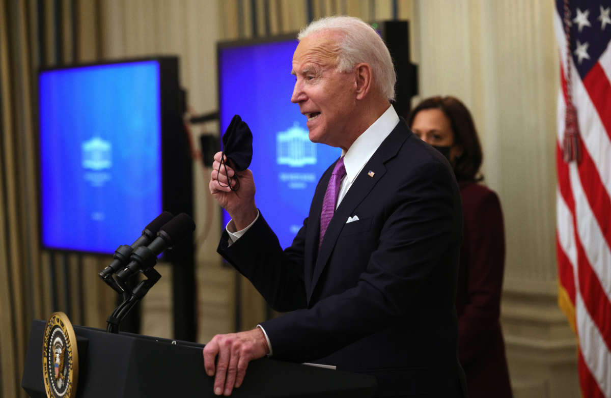 President Biden holds up a mask as Vice President Kamala Harris looks on during an event at the State Dining Room of the White House January 21, 2021, in Washington, D.C.