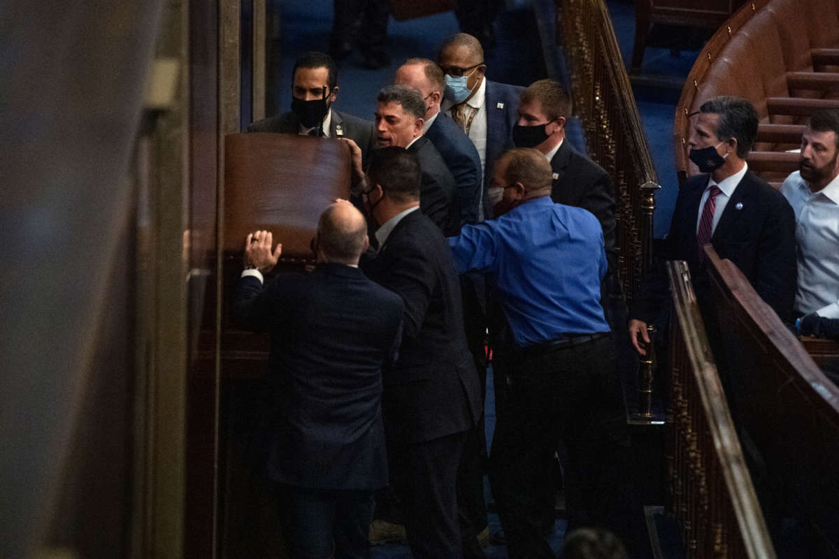 Rep. Andrew Clyde, R-Ga., second from top left, and security barricade the door of the House chamber as rioters disrupt the joint session of Congress to certify the Electoral College vote on Wednesday, January 6, 2021. Reps. Troy Nehls, R-Texas, blue shirt, Markwayne Mullin, R-Okla., right, and Dan Meuser, R-Pa., second from right, are also pictured.