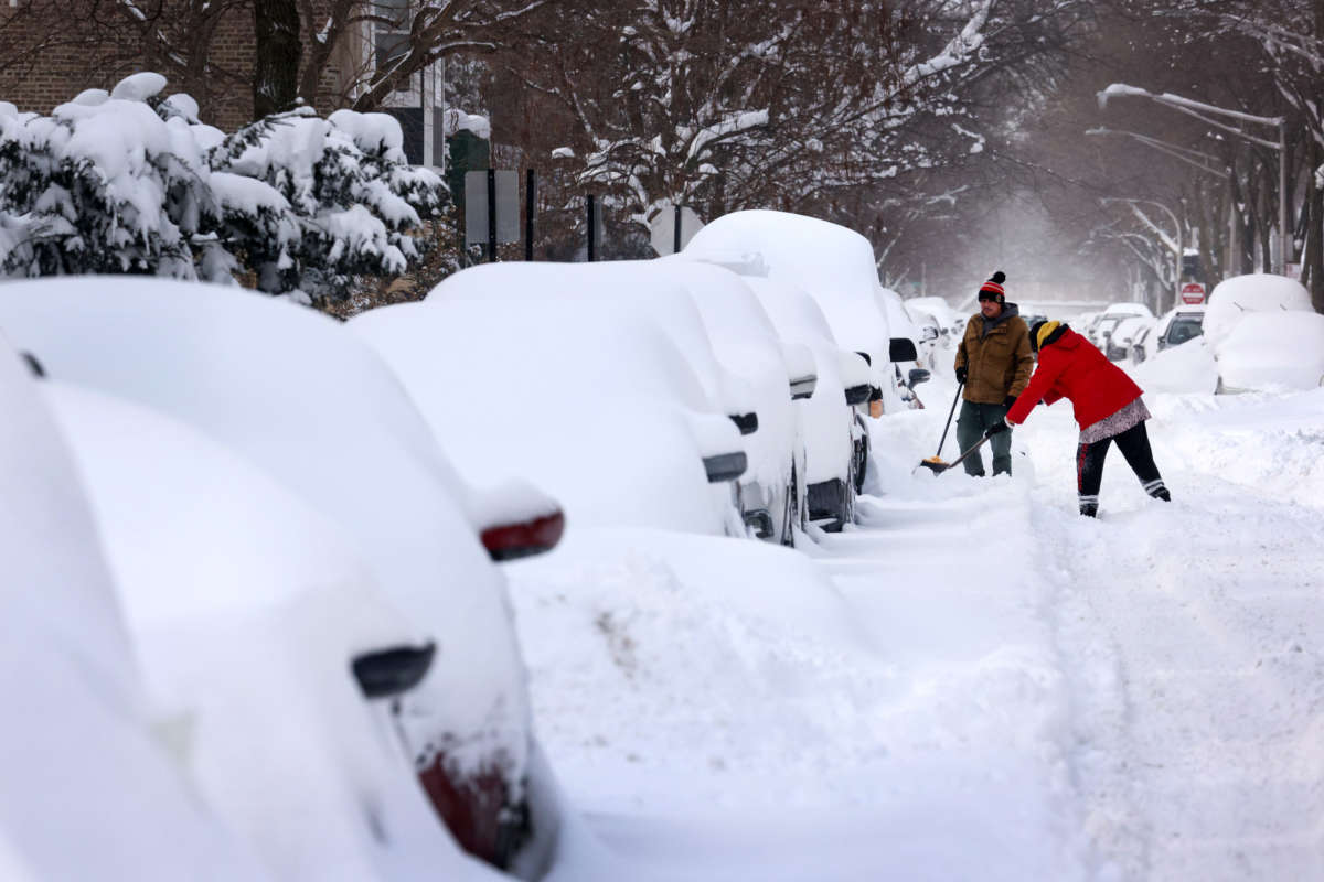 People work to dig out their car along a residential street on February 16, 2021, in Chicago, Illinois.