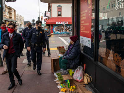 Oakland Deputy Chief of Police Chris Bolton, center, looks at a street vendor while visiting businesses around Chinatown in Oakland, California, February 16, 2021.