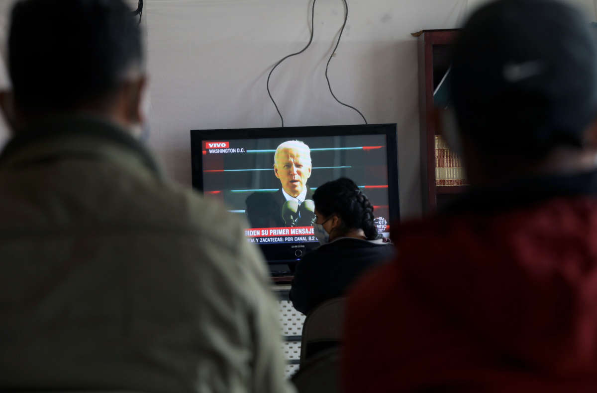 Central American migrants watch a television airing the U.S. Presidential Inauguration ceremony at the Migrant Shelter in Ciudad Juarez, state of Chihuahua, Mexico on January 20, 2021.