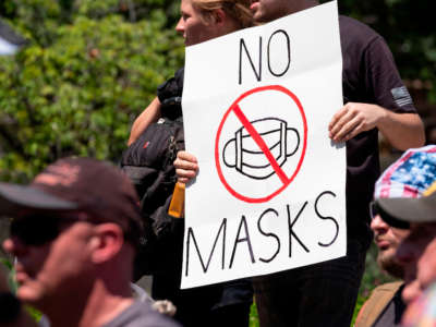 An anti-mask protestor holds up a sign in front of the Ohio Statehouse during a right-wing protest at the State Capitol on July 18, 2020, in Columbus, Ohio.