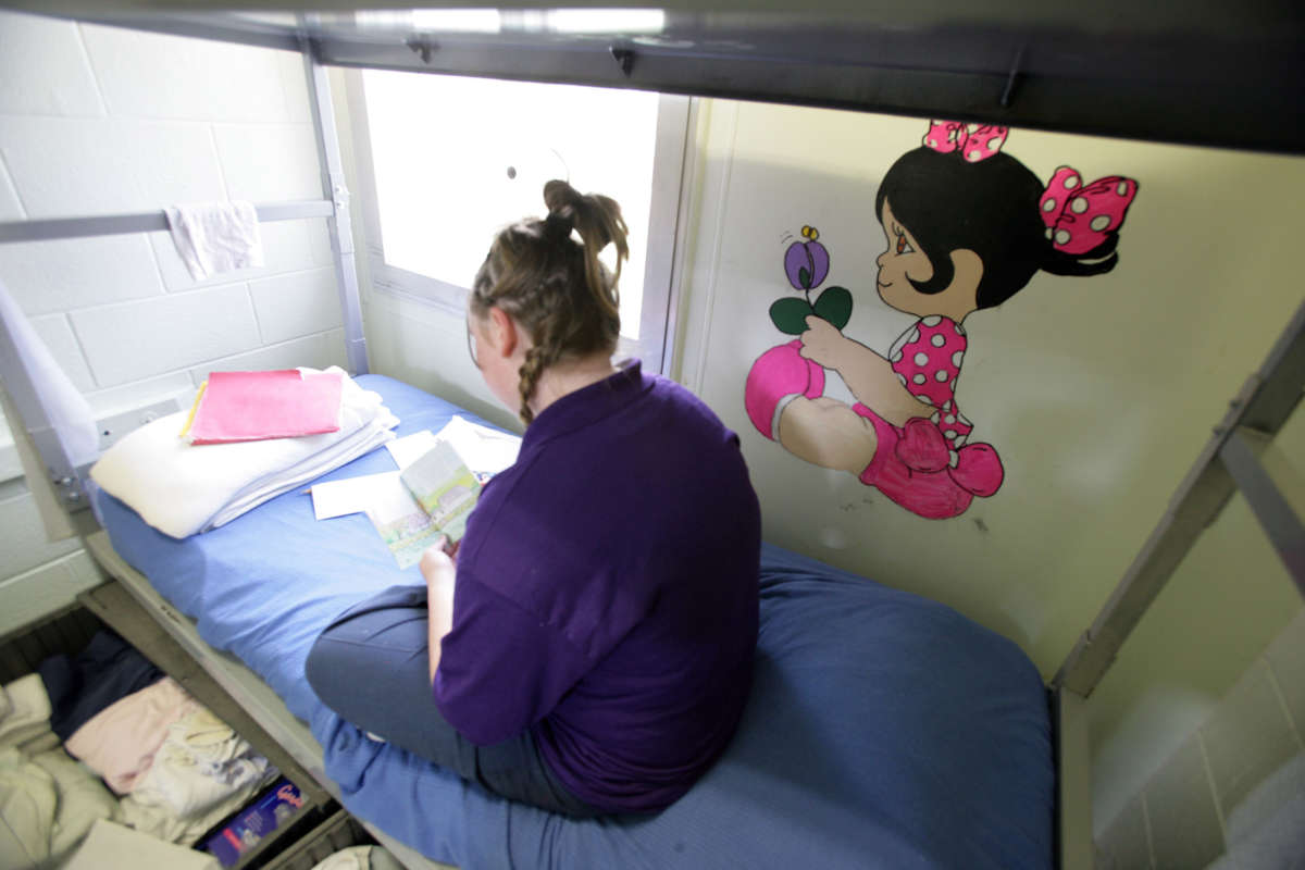 A young inmate at Illinois Youth Center at Warrenville, the state's maximum-security prison for girls, reads on her bed next to a mural on her bedroom wall on June 27, 2007.