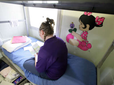 A young inmate at Illinois Youth Center at Warrenville, the state's maximum-security prison for girls, reads on her bed next to a mural on her bedroom wall on June 27, 2007.