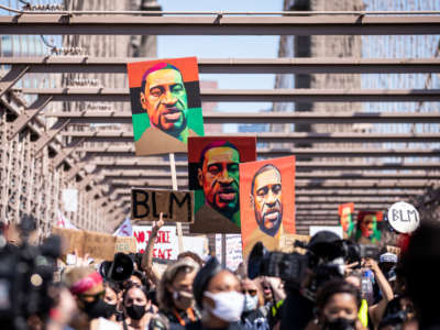 Thousands of protesters march across the Brooklyn Bridge with painted portraits of George Floyd in the Manhattan Borough of New York on June 19, 2020.