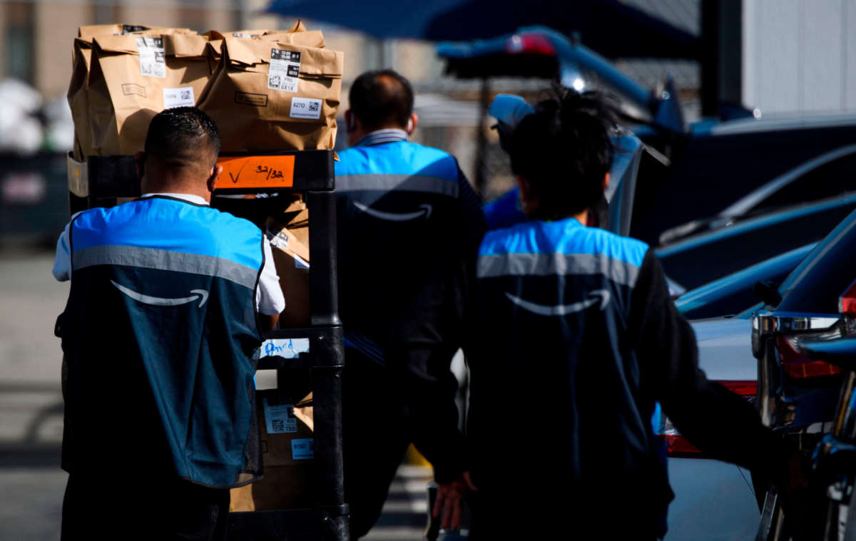 An Amazon delivery driver scans bags of groceries while loading a vehicle outside of a distribution facility on February 2, 2021, in Redondo Beach, California.