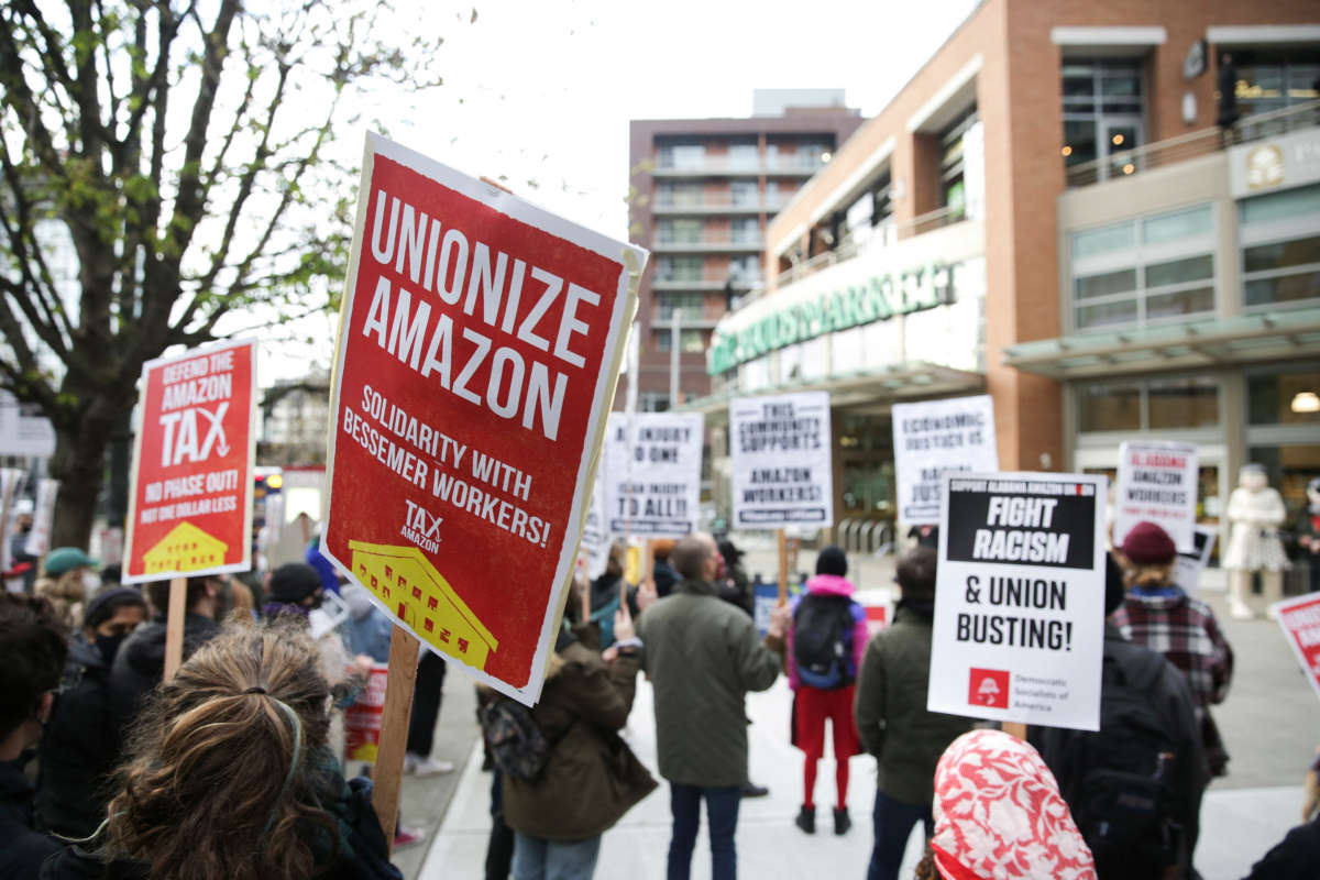 People hold pro-union signs and rally outside a Whole Foods Market after marching from Amazon headquarters in solidarity with Amazon workers in Bessemer, Alabama, who hope to unionize, in Seattle, Washington, on March 26, 2021.