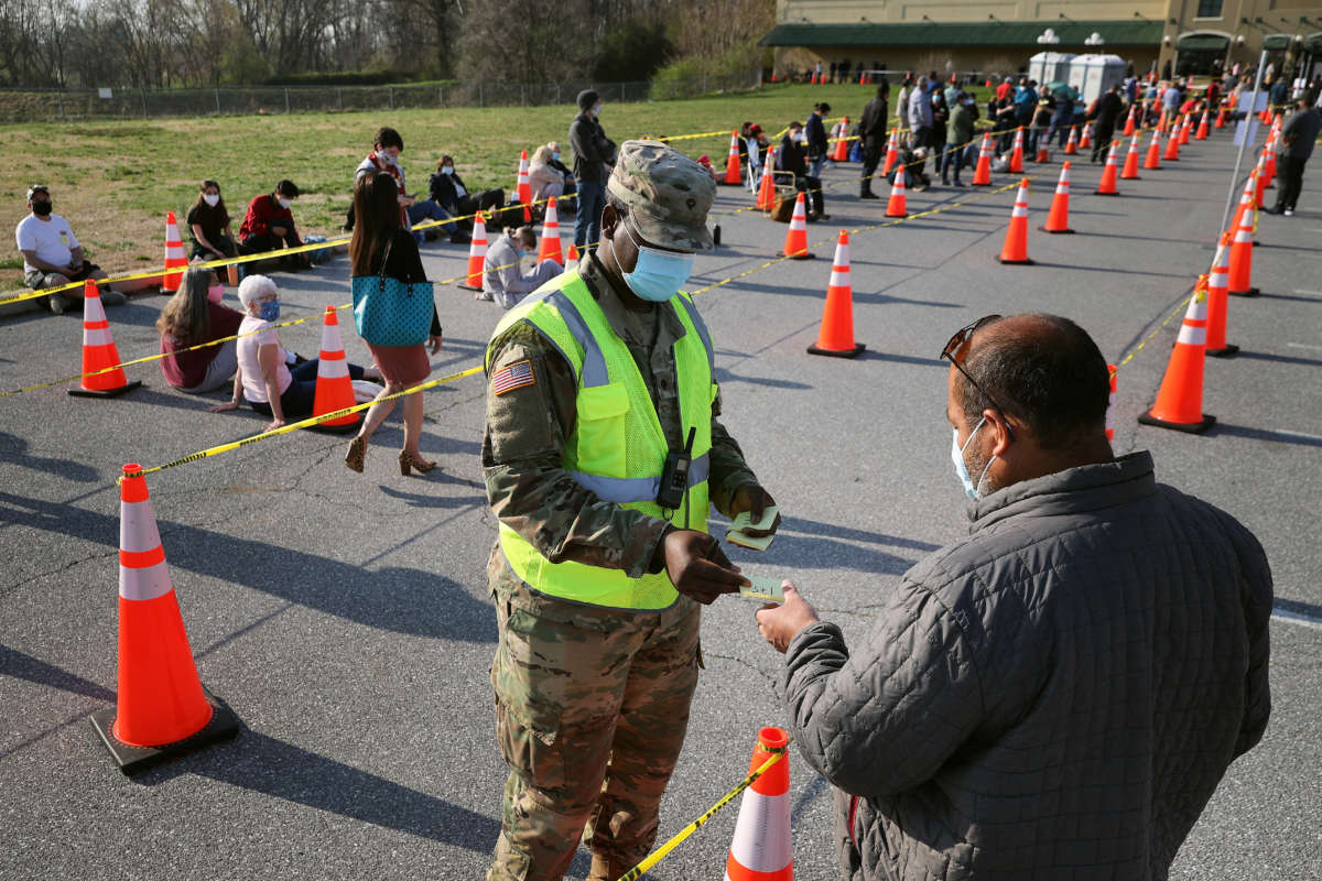 A member of the Maryland National Guard hands out Post-It notes with numbers to people arriving without appointments at the mass coronavirus vaccination site at Hagerstown Premium Outlets on April 7, 2021, in Hagerstown, Maryland.