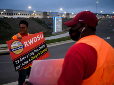 Union organizers wave to cars exiting an Amazon fulfillment center on March 27, 2021, in Bessemer, Alabama.