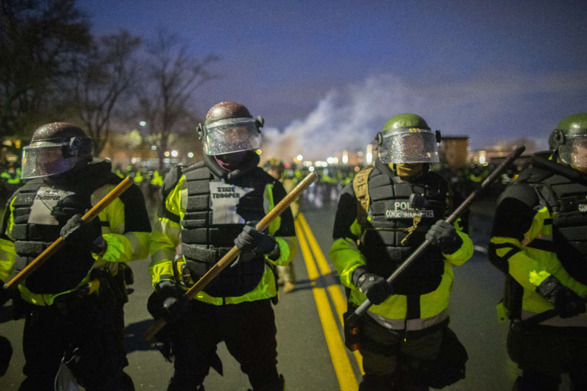 Tear gas rises from behind a line of Minnesota State Troopers as they block the road from anyone going back towards the Brooklyn Center police station where people protest the police killing of Daunte Wright in Brooklyn Center, Minnesota, on April 13, 2021.