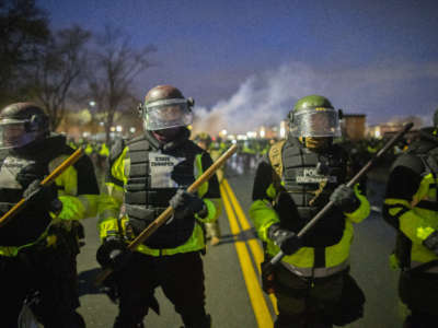 Tear gas rises from behind a line of Minnesota State Troopers as they block the road from anyone going back towards the Brooklyn Center police station where people protest the police killing of Daunte Wright in Brooklyn Center, Minnesota, on April 13, 2021.