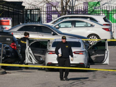 Crime scene investigators walk through the parking lot of the mass shooting site at a FedEx facility in Indianapolis, Indiana, on April 16, 2021.