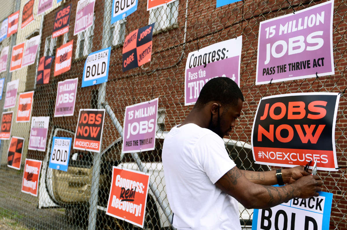 Derrick Davis, a member of West Virginia New Jobs Coalition, hangs up signage during a community gathering and job fair as West Virginians take action for an economic recovery and infrastructure package prioritizing climate, care, jobs, justice and call on Congress to pass the THRIVE Act on April 8, 2021, in Charleston, West Virginia.