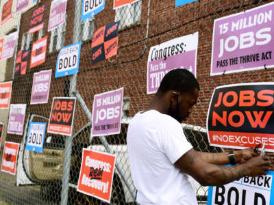 Derrick Davis, a member of West Virginia New Jobs Coalition, hangs up signage during a community gathering and job fair as West Virginians take action for an economic recovery and infrastructure package prioritizing climate, care, jobs, justice and call on Congress to pass the THRIVE Act on April 8, 2021, in Charleston, West Virginia.