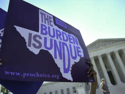 An abortion rights activist holds placards outside of the U.S. Supreme Court before the Court on June 27, 2016, in Washington, D.C.