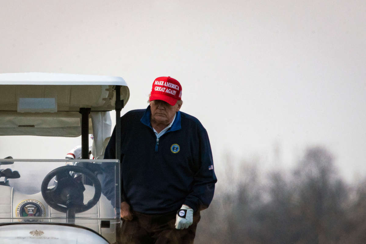 Then-President Donald Trump climbs into golf cart number 45 as he golfs at Trump National Golf Club on December 13, 2020, in Sterling, Virginia.