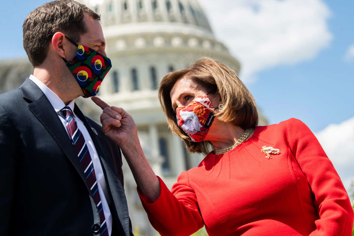 Speaker of the House Nancy Pelosi checks out the mask of Rep. Jason Crow during a news conference outside the Capitol on May 13, 2021.