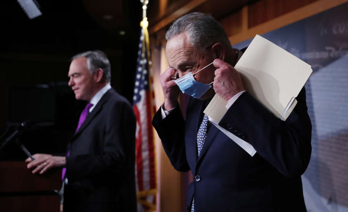 Senate Minority Leader Charles Schumer, right, replaces his surgical mask after yielding the lectern to Sen. Tim Kaine during a news conference at the U.S. Capitol on November 17, 2020, in Washington, D.C.