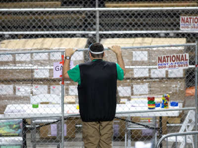 A contractor working for Cyber Ninjas, who was hired by the Arizona State Senate, looks at ballots from the 2020 general election on May 3, 2021, in Phoenix, Arizona.