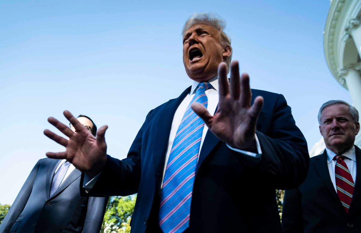 President Donald Trump with White House Chief of Staff Mark Meadows (right) stops to talk to reporters as he walks to board Marine One and depart from the South Lawn at the White House on July 29, 2020, in Washington, D.C.