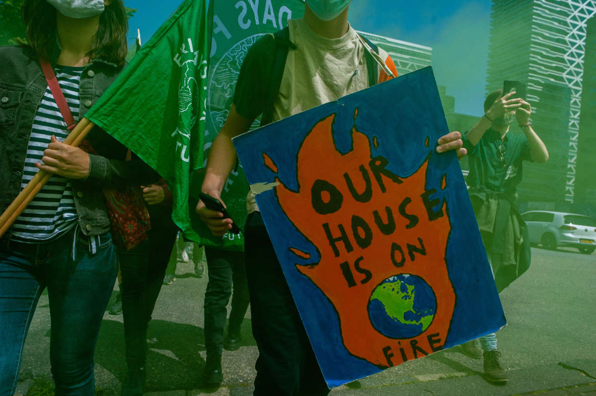 A protester holds a placard reading "Our house is on fire" during a climate demonstration outside the Hague, Netherlands, on June 24, 2021.