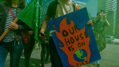 A protester holds a placard reading "Our house is on fire" during a climate demonstration outside the Hague, Netherlands, on June 24, 2021.