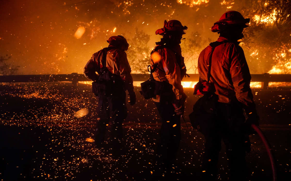 Firefighters turn to shield themselves from the ember wash as they battle the Bond Fire on December 3, 2020, in Silverado, California.