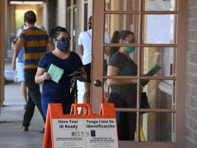 People arrive either to drop off mail-in ballots or vote in person in the U.S. presidential election at an early voting location in Phoenix, Arizona, on October 16, 2020.