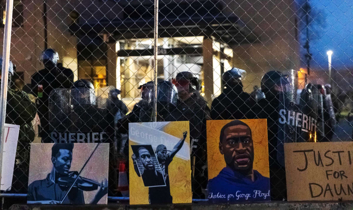 Elijah McClain and George Floyd pictures left by demonstrators line up the fence outside the Brooklyn Center police station while protesting the death of Daunte Wright, who was shot and killed by a police officer, in Brooklyn Center, Minnesota, on April 14, 2021.