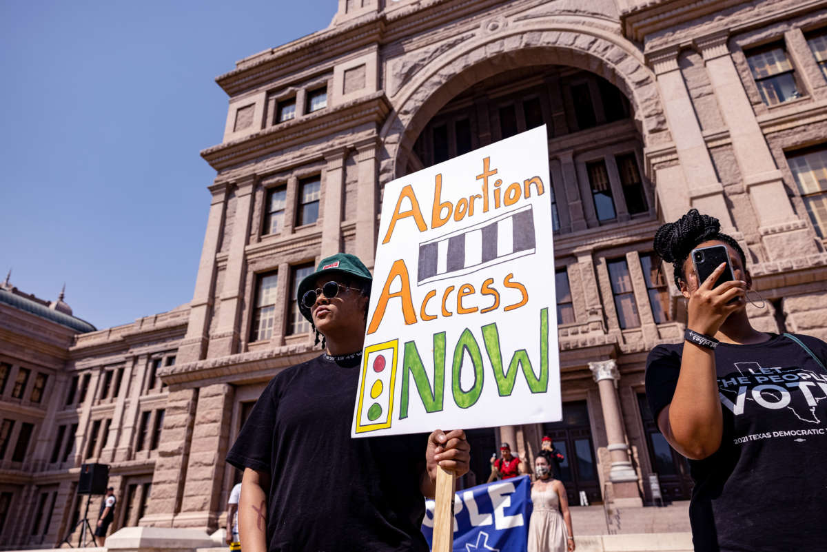 A protester displays a sign reading "ABORTION ACCESS NOW" during an action