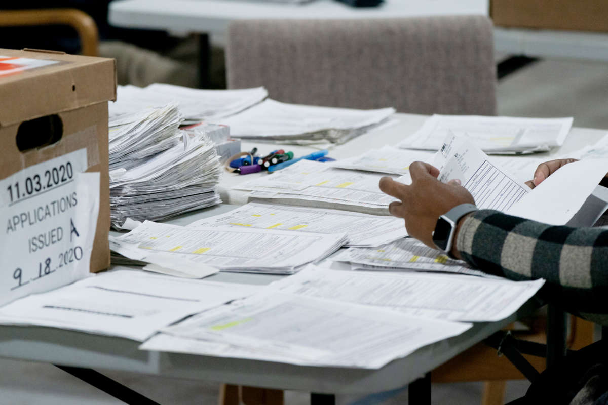 A worker sorts through stacks of paper