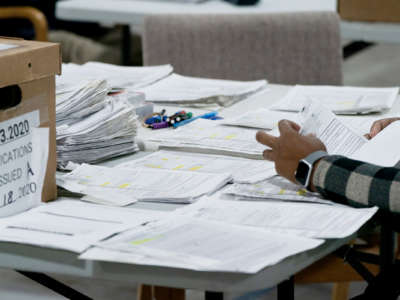 A worker sorts through stacks of paper