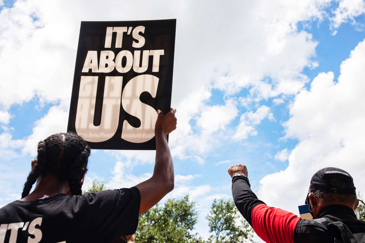 People display signs, one of which reads "IT'S ABOUT US," during a protest