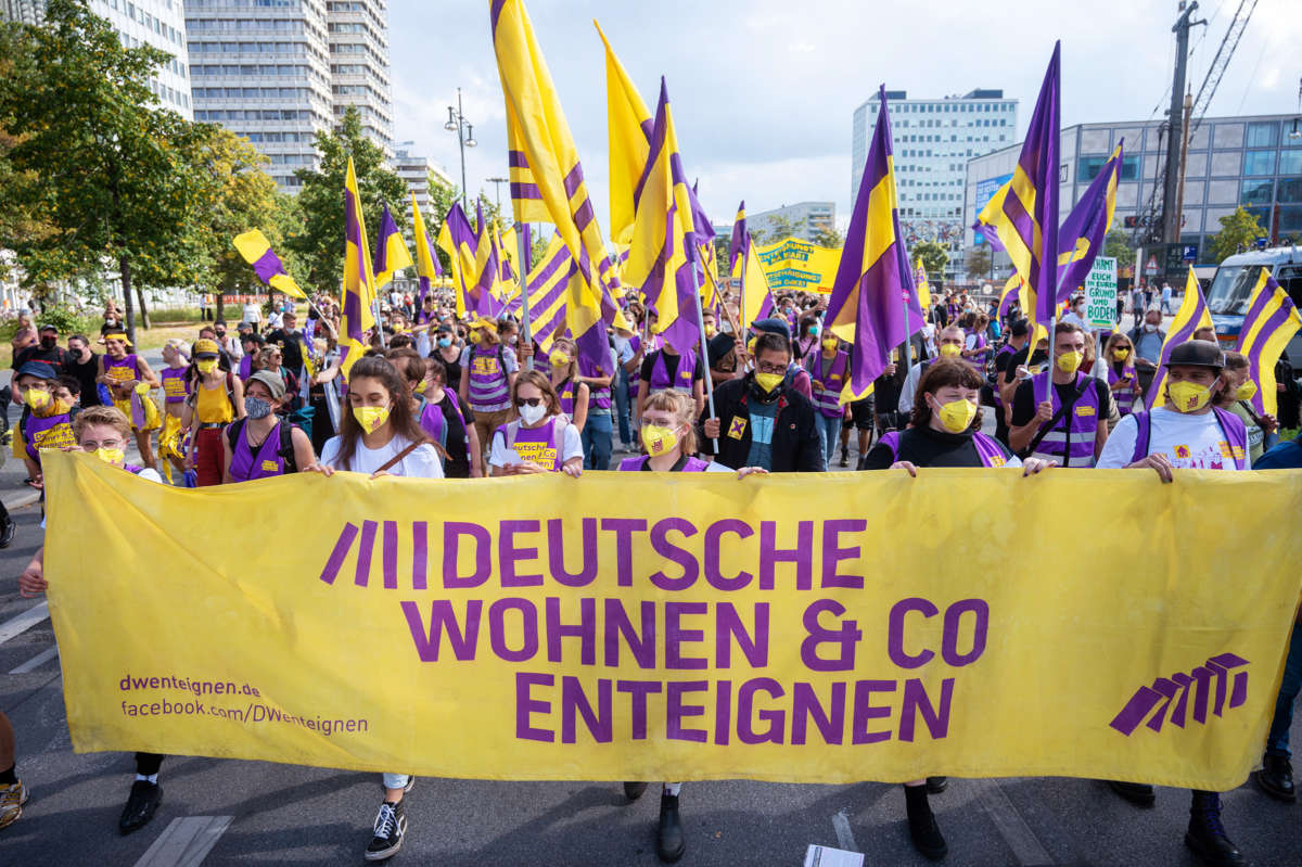 People walk behind a banner with German text